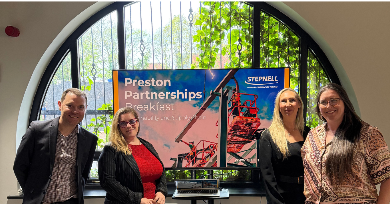 Sustainability Toolkit - workshop with Stepnell and Preston Partnership. 4 Colleagues are sending in front of a branded screen, smiling at the camera